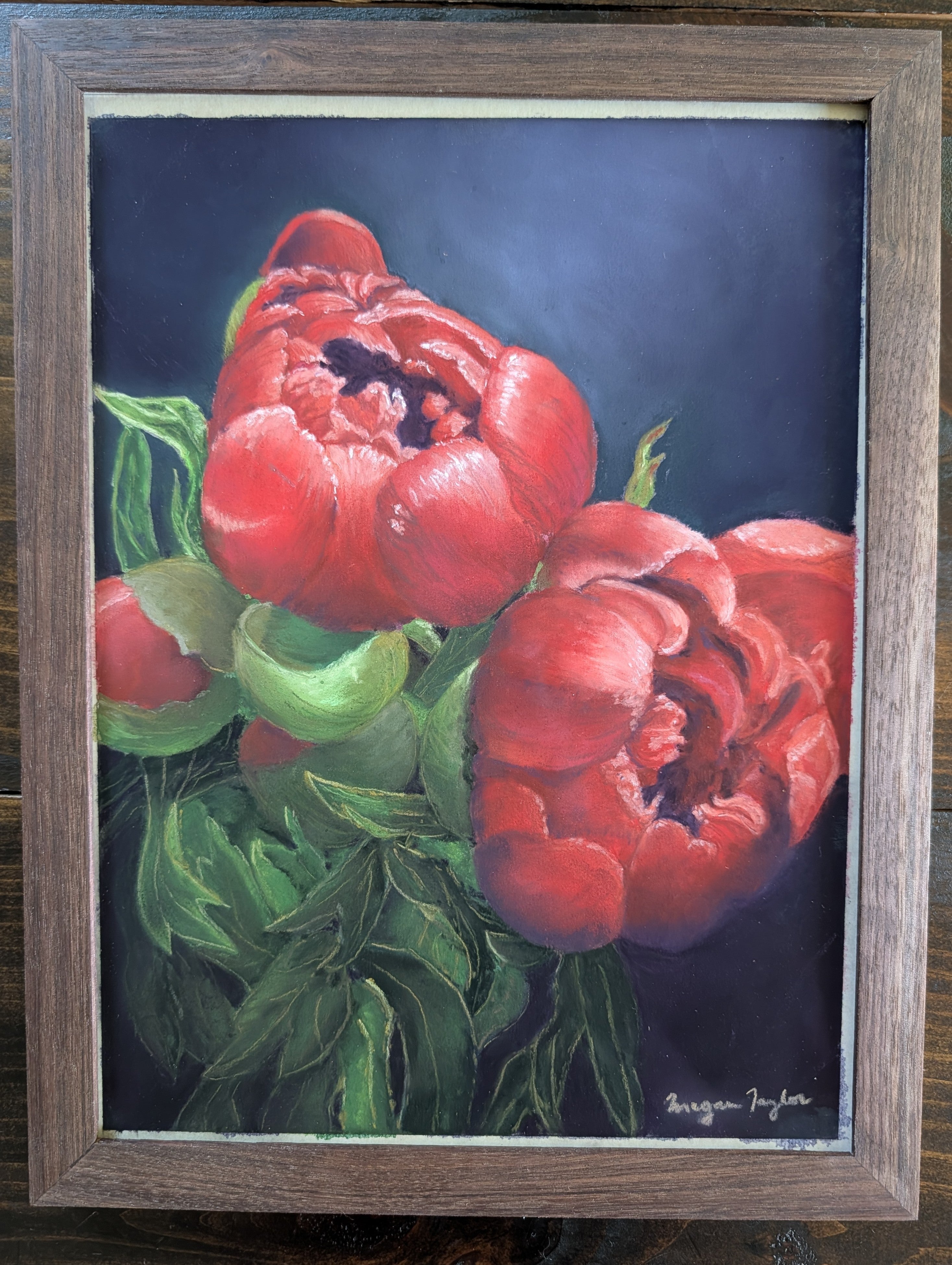 Framed artwork of red flowers with green leaves on a dark background
